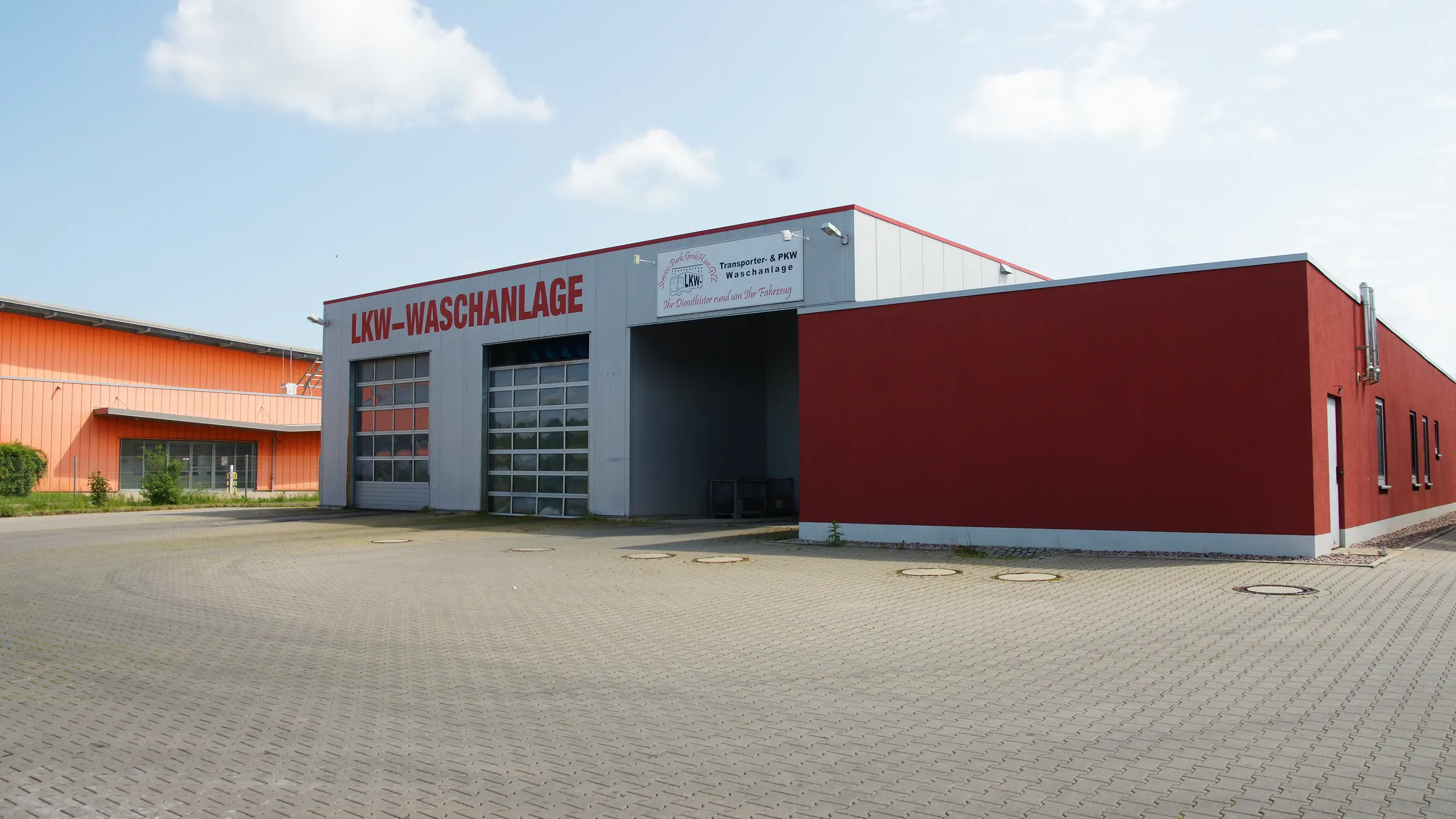 Waschhalle des Service-Park von der Zufahrt aus, an der Fassade der rote Schriftzug LKW-WASCHANLAGE