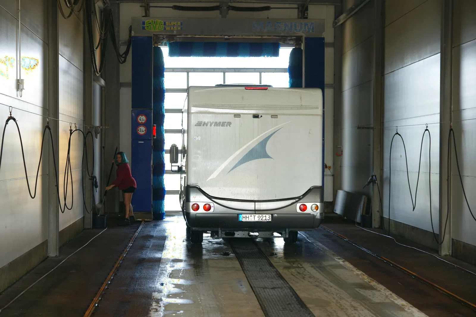 Wohnmobil steht in der Waschhalle vor dem Portal mit den blauen Waschbürsten